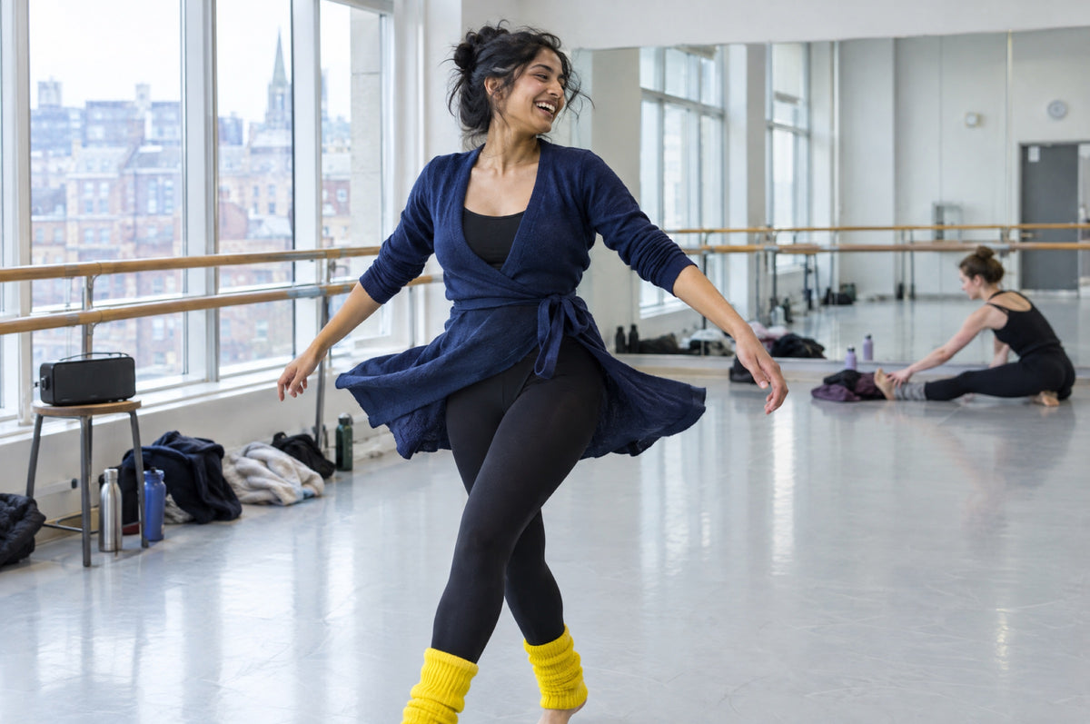 A young woman spins mid-dance in a bright studio wearing yellow leg warmers.