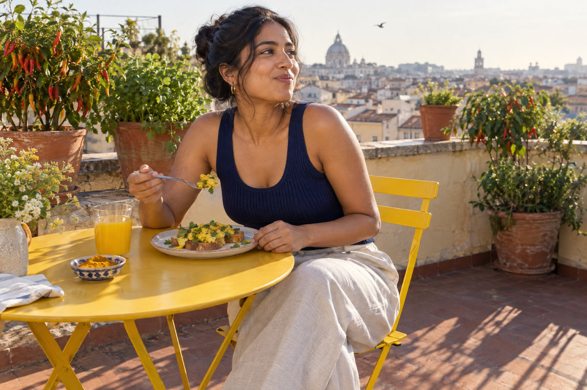 A young woman eats golden scrambled eggs at a rooftop table on a yellow chair.